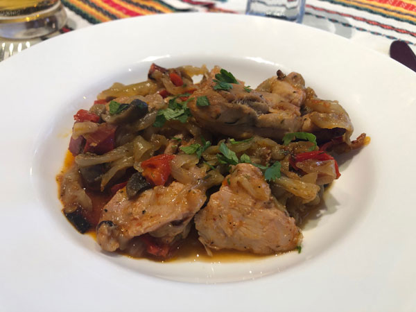 A plate of chicken cooked with vegetables, including peppers and onions, garnished with fresh parsley.